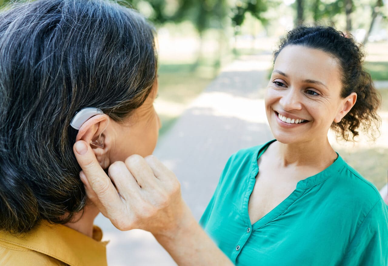 Woman with hearing aid talking to her friend outside.