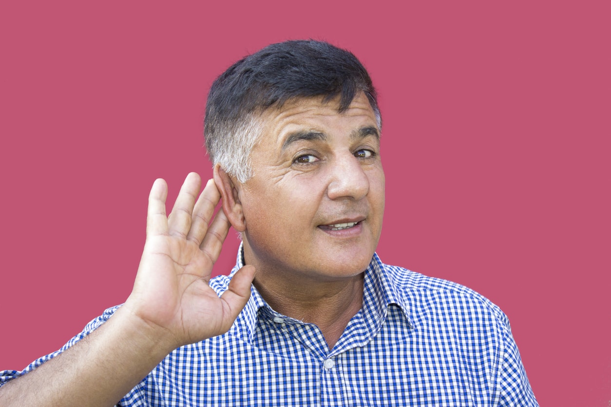 Man putting his hand to his ear to hear.