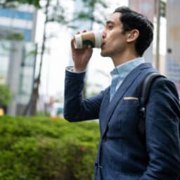 Man with hearing loss in city drinks coffee