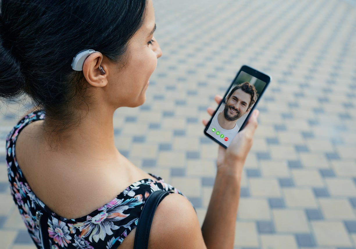 woman with a hearing aid behind the ear communicates with her boyfriend via video call