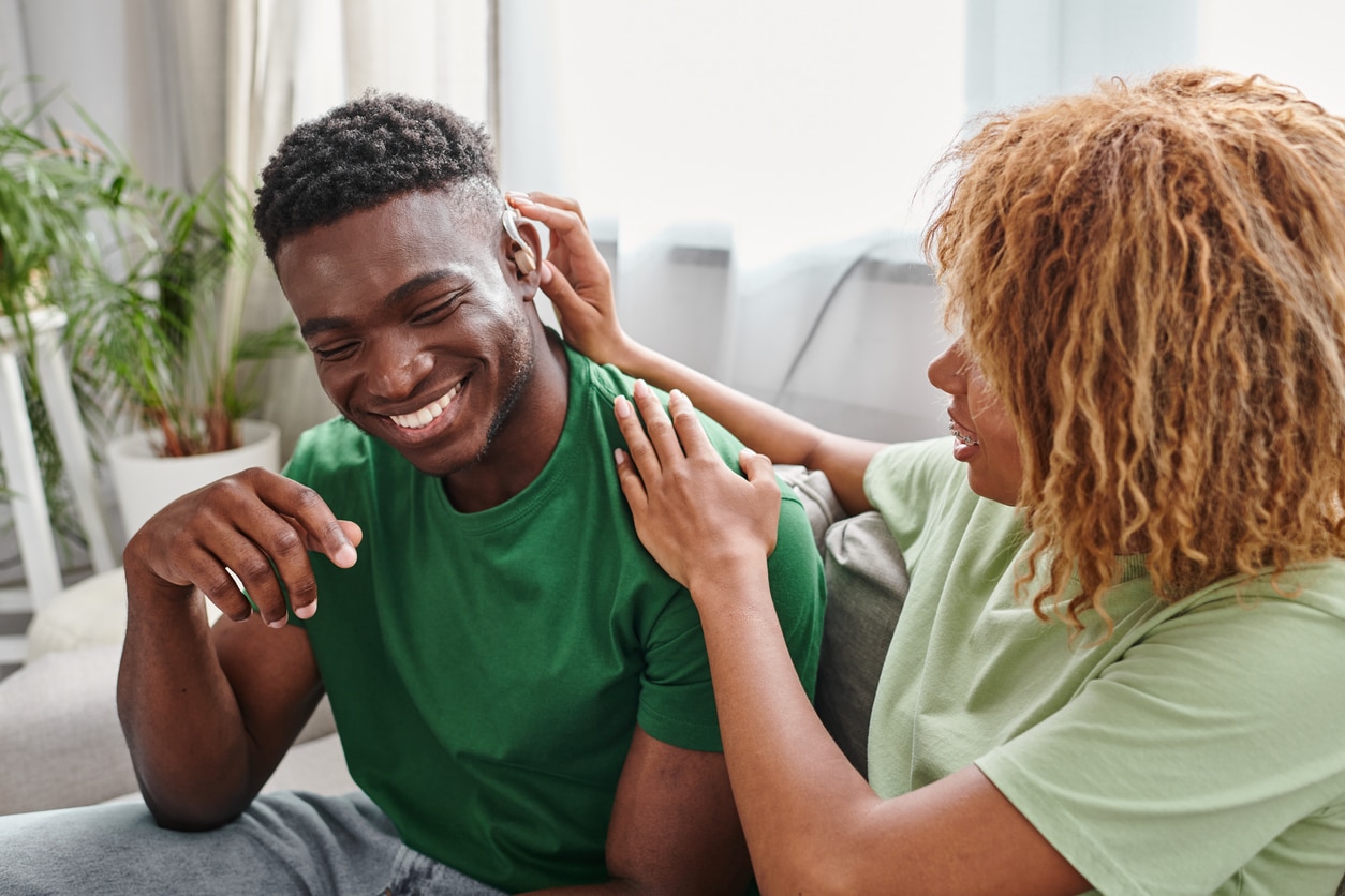 Happy couple, man wearing a new hearing aid.
