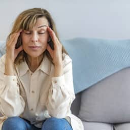 Stressed woman massaging her temples while sitting on a couch