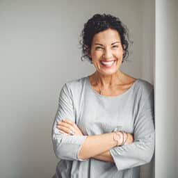 Smiling woman leaning against a doorframe.
