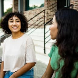Two women sitting on the bench and talking.
