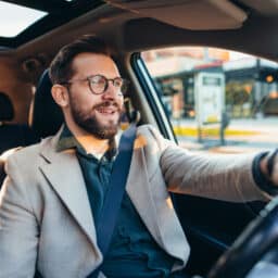 Businessman driving car in city during sunny day