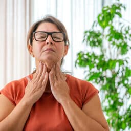 Woman trying to feel her thyroid with both hands.
