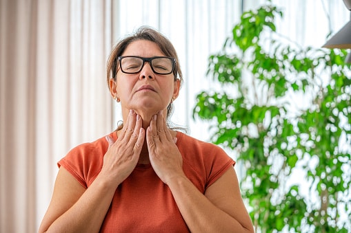 Woman trying to feel her thyroid with both hands.