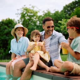 Happy man and his family enjoying in summer holiday by the pool