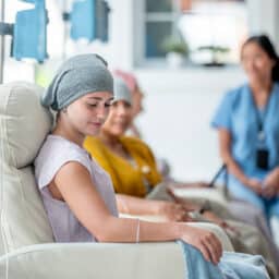 A group of patients undergoing chemotherapy in a comfortable clinical environment, with a supportive nurse present.