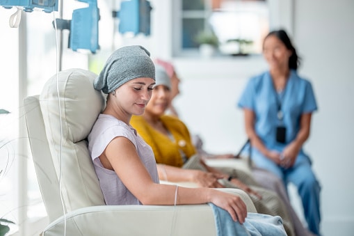 A group of patients undergoing chemotherapy in a comfortable clinical environment, with a supportive nurse present.