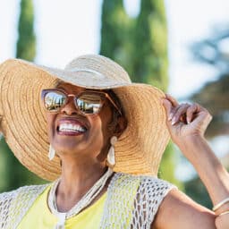 Smiling senior woman in a sun hat outdoors.