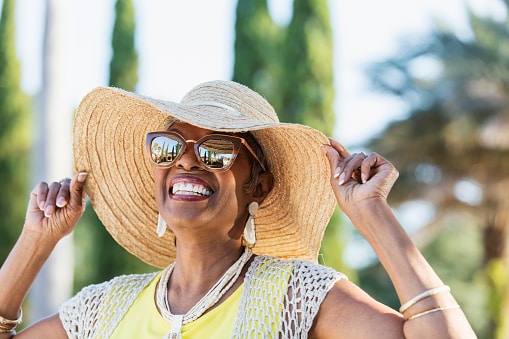 Smiling senior woman in a sun hat outdoors.